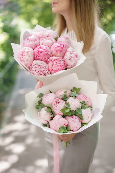 peonies. Young girl holding a flower. Two Beautiful summer bouquet. Arrangement with mix flowers peony. The concept of a flower shop. Content for the catalog