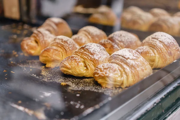 Muchos de croissants. Pasteles calientes se encuentran en el estante de la cafetería. Bollos y rosquillas en la tienda . — Foto de Stock