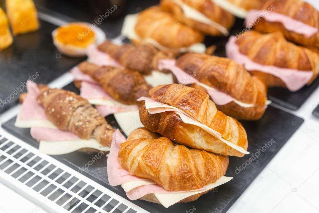 Croissant with ham and cheese. Hot pastries lie on the shelf in the cafe. Buns and bagels in the store.