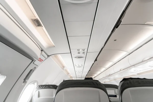 Emergency exit on an aircraft, view from inside of the plane. Empty airplane seats in the cabin. Modern Transportation concept. Aircraft long-distance international flight