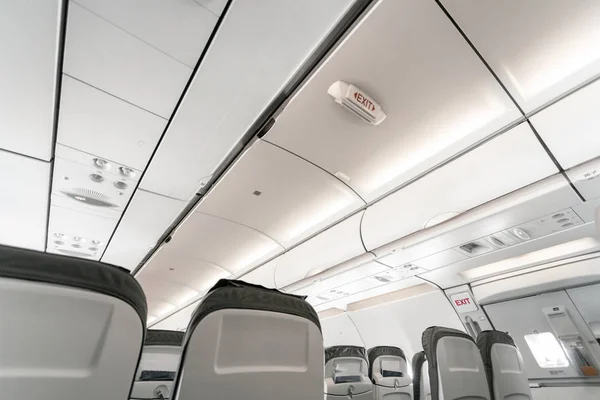 Emergency exit on an aircraft, view from inside of the plane. Empty airplane seats in the cabin. Modern Transportation concept. Aircraft long-distance international flight