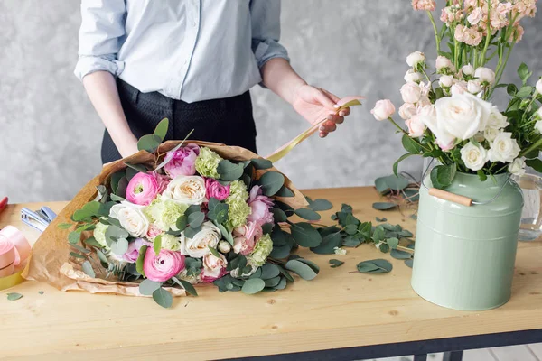 Mujer florista creando hermoso ramo en la tienda de flores. Trabajando en floristería. Asistente o propietaria en estudio de diseño floral, haciendo decoraciones y arreglos . — Foto de Stock