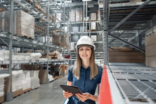 Belle jeune femme ouvrière de magasin de meubles dans le centre commercial. Fille à la recherche de marchandises avec une tablette vérifie les niveaux d'inventaire dans un entrepôt. Concept logistique — Photo