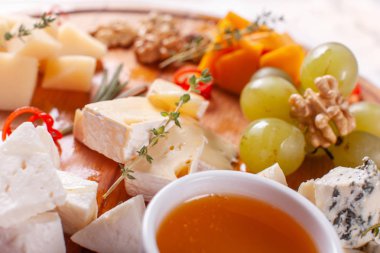 Peynir tabağı. Lezzetli peynir karışımı ile ceviz, bal, üzüm ahşap masa üzerinde. Ahşap bir tabakta yemek tatma. Yiyecek şarap.