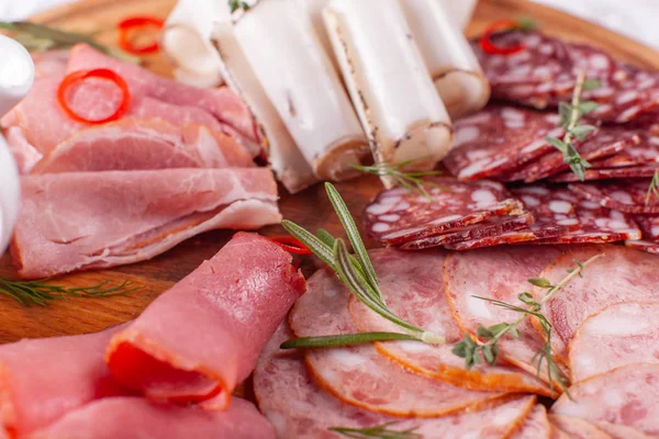 Поднос с вкусной салями, кусочки нарезанной ветчины, колбаса. Резать колбасу и мясо на праздничном столе . — стоковое фото