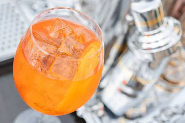 Коктейль Aperol spritz в туманном стекле, избирательный фокус. Алкогольный напиток на основе барной стойки со льдом и апельсинами. металлические шейкеры на заднем плане — стоковое фото