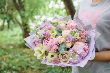 Güzel yaz buket. Mix çiçek aranjmanı. Bir çiçek grup şakayık ile tutan genç kız. Bir çiçekçi dükkanı kavramı. Katalog için içerik