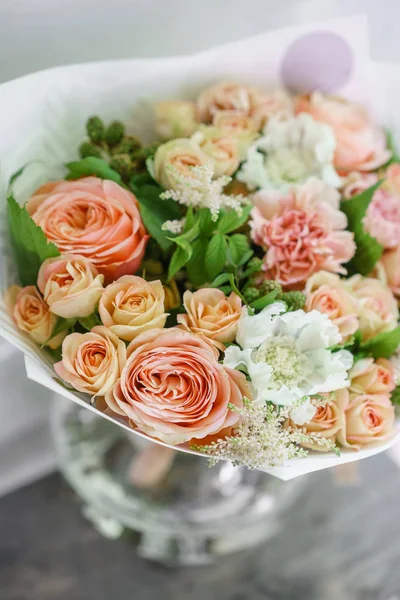 Work florist. Beautiful spring bouquet. Arrangement with mix flowers. The concept of a flower shop, a small family business. Color light peach and orange