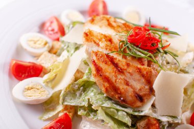 Bıldırcın yumurtası, cherry domates, Parmesan peyniri ve ızgara tavuk masa lambası beyaz tabakta, Sezar salatası.