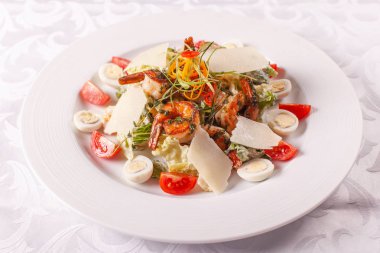 Bıldırcın yumurtası, cherry domates, Parmesan peyniri ve masa lambası beyaz tabakta ızgara karides Sezar salatası.