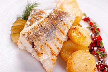 Kavrulmuş cod, beyaz arka plan restoran hizmet üzerinde morina ile fırında patates ve salatalık turşusu ve otlar ile sebze sos. Restoran menü