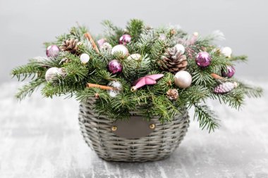 Çam kozalakları, çam dalları, eski ahşap arka plan dekoratif topları ile bir hasır sepet ile Noel ve yeni yıl tebrik kartı. Vintage tarzı seçici odak. arka plan üzerinde ışıklar çelenk
