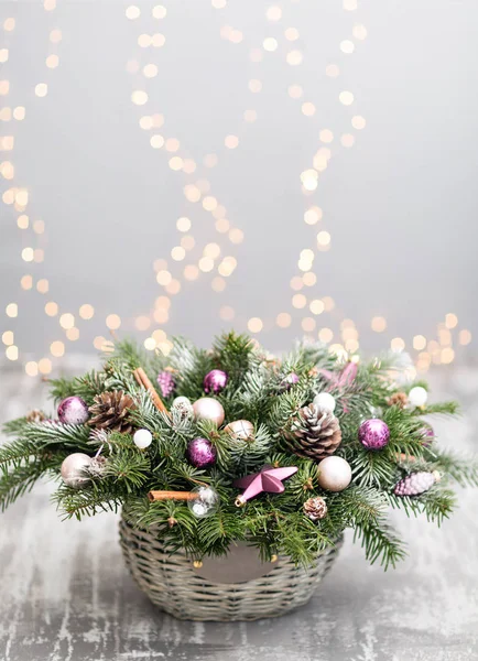Çam kozalakları, çam dalları, eski ahşap arka plan dekoratif topları ile bir hasır sepet ile Noel ve yeni yıl tebrik kartı. Vintage tarzı seçici odak. arka plan üzerinde ışıklar çelenk