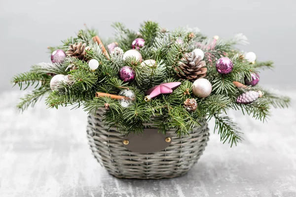 Carte de vœux de Noël ou Nouvel An avec panier en osier avec cônes de pin, branches de sapin, boules décoratives sur un vieux fond en bois. Style vintage, focus sélectif. sur les lumières de fond guirlande — Photo