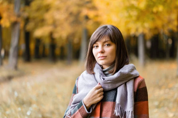 Portrait de jeune femme de mode en plein air. Brunette femme dans le parc d'automne avec manteau à carreaux à la mode et écharpe . — Photo