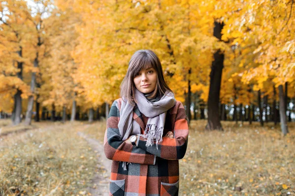 Porträt einer jungen Modefrau im Freien. brünette Frau im Herbstpark mit modischem karierten Mantel und Schal. — Stockfoto