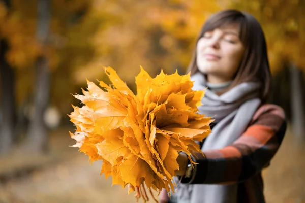 Céntrate en las hojas amarillas. Mujer morena en el parque de otoño con abrigo a cuadros de moda y bufanda . —  Fotos de Stock