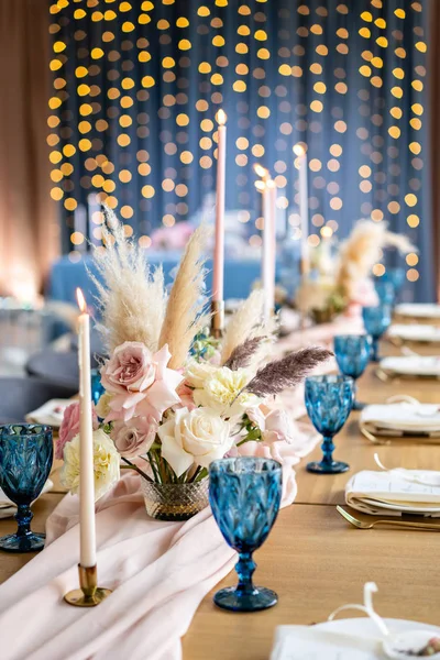 luxury dinner Banquet in the restaurant. Beautiful and exquisite decoration of the wedding celebration. Banquet served table with a beige pink tablecloth, plates and candlesticks with candles.