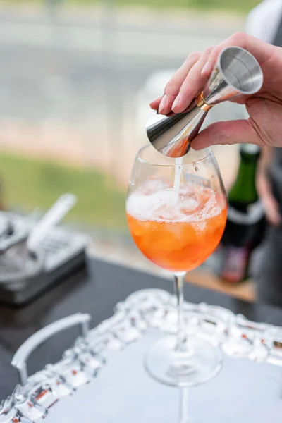 Bartender makes cocktail Aperol spritz. Misted glass, selective focus. Alcoholic beverage based on bar counter with ice cubes and oranges. outdoor party — Stock Photo, Image