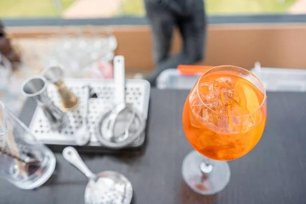 Cóctel Aperol spritz en vidrio nebulizado, enfoque selectivo. Bebida alcohólica basada en barra de bar con cubitos de hielo y naranjas. agitadores de metal en el fondo — Foto de Stock