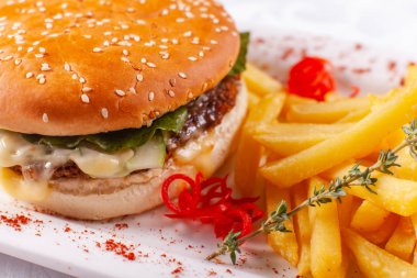 Fast food restoran menü. Ev yapımı hamburger sığır köftesi, soğan, domates, marul ve peynir ile. Taze hamburger yakın çekim. Altın patates kızartması patates ile süslenmiş
