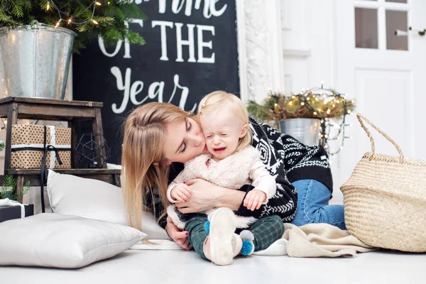 Babys pláč. Veselá maminka objímá její roztomilý dcera. Rodič a dítě baví poblíž vánoční stromeček doma. Milující rodiny Veselé Vánoce a šťastný nový rok — Stock fotografie
