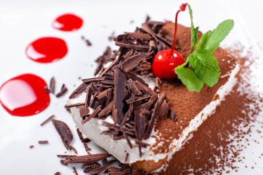 Tiramisu. Kakao ve çikolata beyaz kare plaka ile klasik tatlı. Kiraz ve nane ile süslenmiş. Şekerli tatlı restoranda. Sabah güneşi