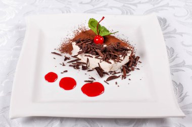 Tiramisu. Kakao ve çikolata beyaz kare plaka ile klasik tatlı. Kiraz ve nane ile süslenmiş. Şekerli tatlı restoranda. Sabah güneşi