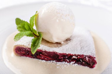 Berry strudel pasta dondurma, nane yaprağı ve vanilya sosu ile servis. Beyaz tabakta klasik Avusturya tatlı. Şekerli tatlı restoranda. Sabah güneşi.