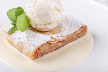 Meyve elma strudel pasta dondurma, nane yaprağı ve vanilya sosu ile servis. Beyaz tabakta klasik Avusturya tatlı. Şekerli tatlı restoranda. Sabah güneşi.