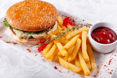 Fast food restoran menü. Ev yapımı hamburger sığır köftesi, soğan, domates, marul ve peynir ile. Taze hamburger yakın çekim. Altın patates kızartması patates ile süslenmiş