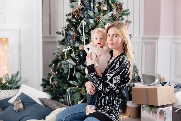 Neşeli anne şirin bebek kızını kucaklıyor. Anne-baba ve küçük çocuk kapalı Noel ağacı yakınındaki eğleniyor. Sevgi dolu aile mutlu Noeller ve mutlu yeni yıl — Stok fotoğraf