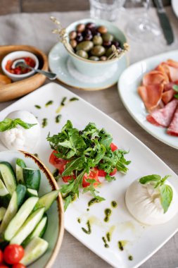 İtalyan Caprese salatası. burrata peynir, domates ve fesleğen bitki yaprakları. Beyaz tabakta düzenlenmiş balsamik sirke