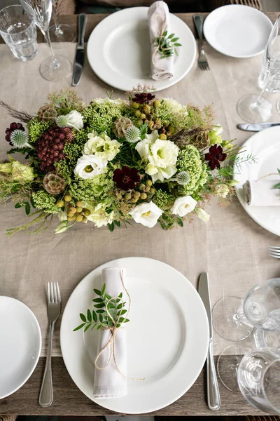 Bem torcido em um guardanapo de sala de jantar tubo decorado com um raminho de pistache. Banquete de casamento ou jantar de gala. As cadeiras e mesa para os hóspedes, servidos com talheres e louças. festa no terraço — Fotografia de Stock