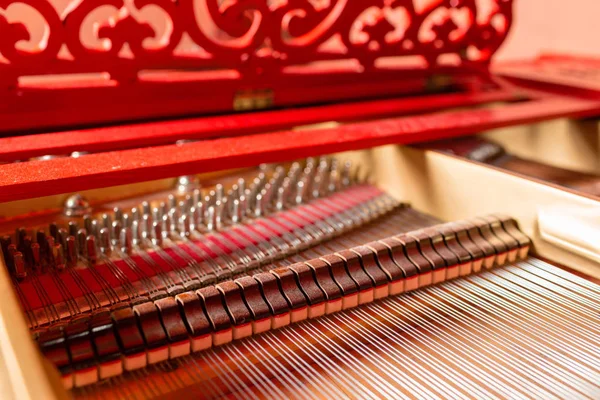 Strings inside a red grand piano. Piano playing, dampers, felt hammers, bronze strings and metal frame. — Stock Photo, Image