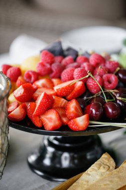 İş veya düğün olay mekanı ziyafet masada taze meyve tabağı. Self servis veya tüm olabilir yemek - ahududu, çilek, kiraz, incir, apricote. Soğuk aperatifler ve sofra içeren tablo