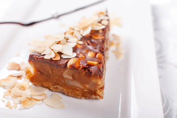 Nuts cake. Piece of Cake with almond ant peanut on a Plate. Sweet food. Sweet dessert. Food background. Close up. — Stock Photo, Image