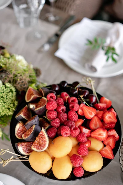 Fresh Fruit platter on banquet table at business or wedding event venue. Self service or all you can eat - raspberry, strawberry, cherry, Fig, apricote. Table with cold snacks and tableware