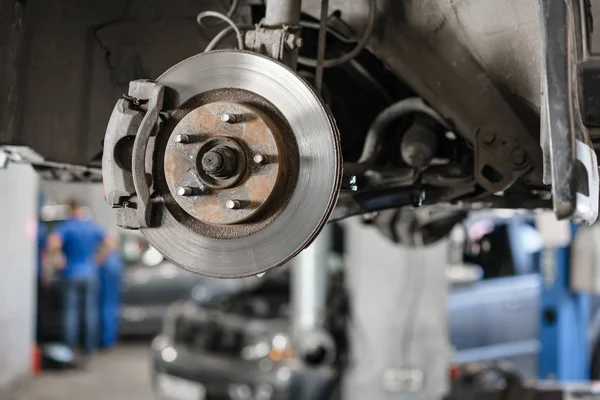 Carro mecânico inspecionando roda do carro e reparar detalhe suspensão. Elevado automóvel na estação de serviço de reparação. substituição de ferrule e alavancagem — Fotografia de Stock