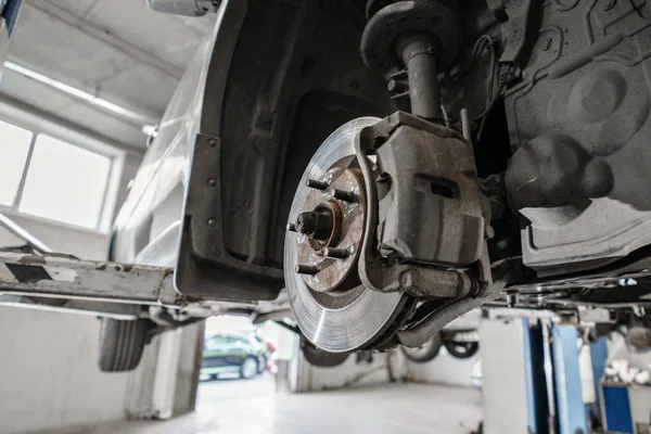 Carro mecânico inspecionando roda do carro e reparar detalhe suspensão. Elevado automóvel na estação de serviço de reparação. substituição de ferrule e alavancagem — Fotografia de Stock