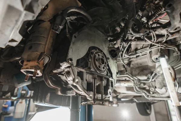 Cambio y reparación de embrague, eje motriz. trabajando debajo de un coche levantado. Trabajo mecánico profesional coche de mantenimiento. Garaje servicio de coches . — Foto de Stock