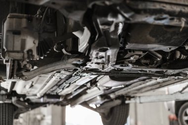 Araba tamircisi araba tekerleğini inceliyor ve süspansiyon detaylarını onarıyor. Tamir istasyonunda otomobil kaldırmış. Doğurganlık ve kaldıraç değişimi