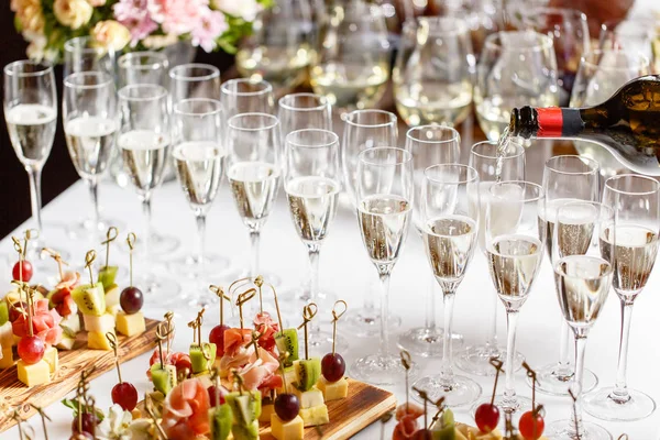 Barista versando champagne o vino in bicchieri di vino sul tavolo del ristorante. solenne cerimonia nuziale o felice anno nuovo banchetto — Foto Stock