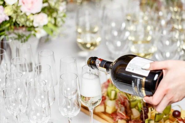 Cantinero vertiendo champán o vino en copas de vino sobre la mesa en el restaurante. solemne ceremonia de boda o feliz año nuevo banquete —  Fotos de Stock