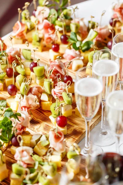 Торжественный новогодний банкет. Много бокалов шампанского или вина на столе в ресторане. шведский стол с большим количеством вкусных закусок. канапе, брускетта и маленькие десерты на деревянной доске — стоковое фото