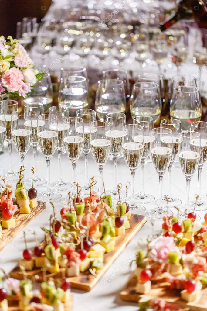 Bartender pouring champagne or wine into wine glasses on the table in restaurant. solemn wedding ceremony or happy new year banquet