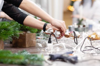 Bir kadın bir Noel düzenleme mumlar ile süsle. Eller yakın çekim. Ana sınıf dekoratif süsler yapmak. Noel dekor kendi elleriyle. Yeni yıl kutlama. Çiçekçi Dükkanı