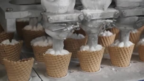 Робот-машина автоматически наливает мороженое в вафельные чашки. Автоматические конвейерные линии для производства рожков мороженого. Вафельные чашки и колбочки. Большое промышленное производство . — стоковое видео