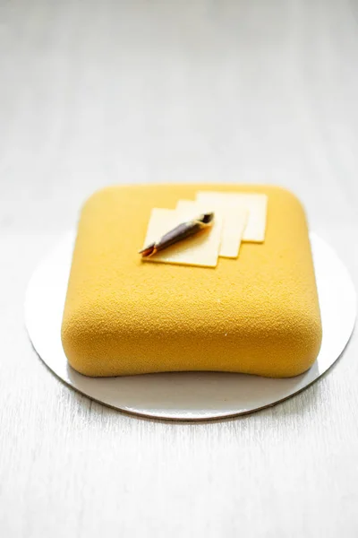 Elegance fyrkantig velour mousse tårta. mutter och frukt fyllning inuti. Samtida gul cirkel. selektivt fokus. vitt bord. — Stockfoto