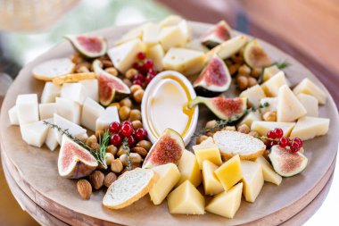 Peynir tabağı. Lezzetli peynir karışımı baget kruton, frenk üzümü, tatlı incir, badem, bal ahşap masa üzerinde. Ahşap bir tabakta yemek tatma. Yiyecek şarap için. Keçi peyniri, Parmesan, Gouda